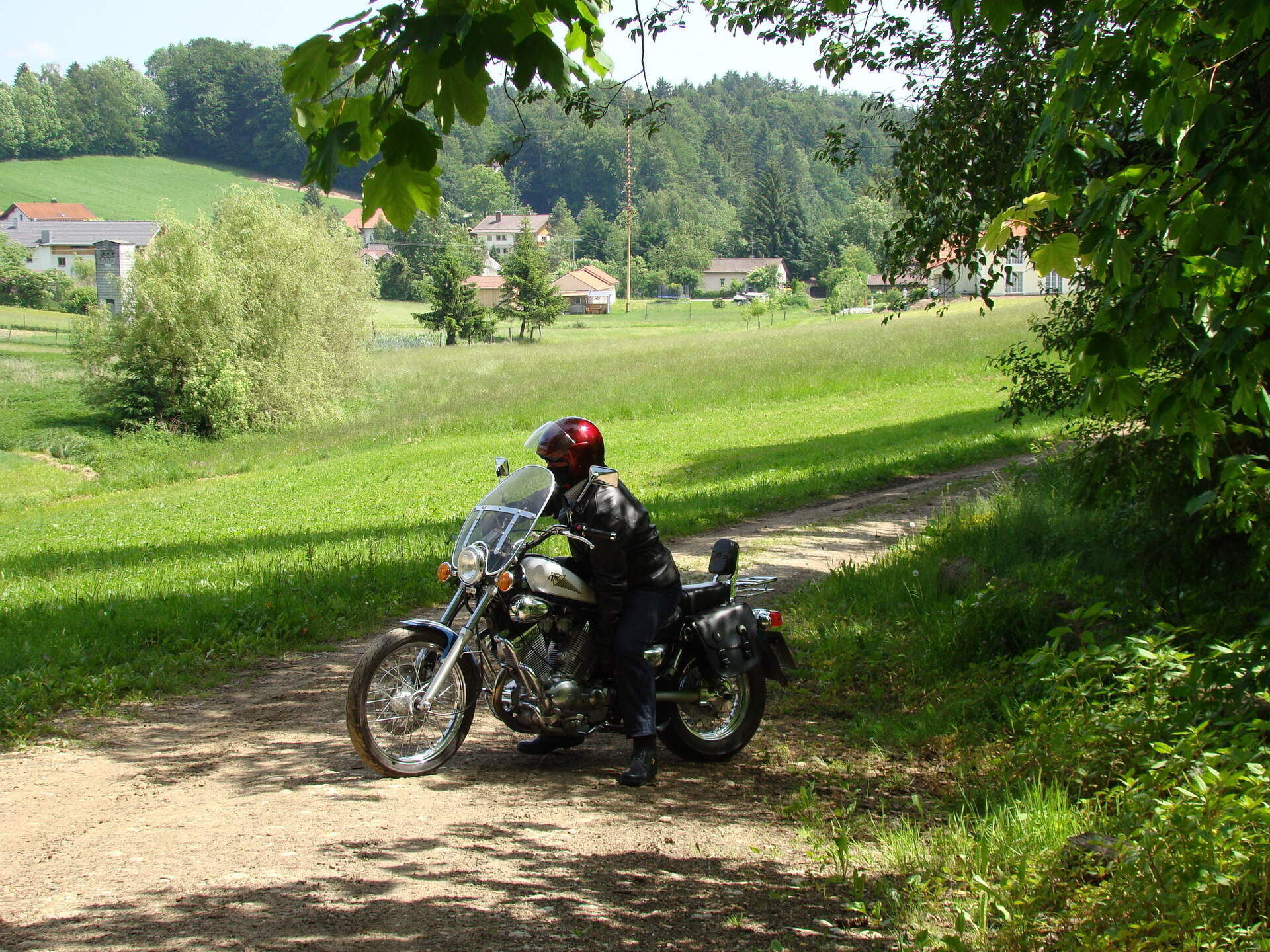 Ein Motorradfahrer macht eine Pause auf einem Feldweg im Bayerischen Wald.